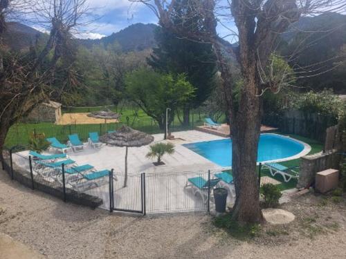 una piscina con sillas azules y un árbol en Le Moulin du Béal, en Aubres