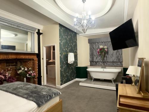 a bathroom with a tub and a bed and a television at Scole Inn Hotel in Diss