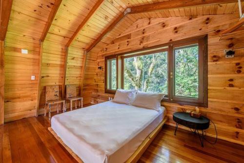 a bedroom in a log cabin with a bed and a window at Ateliê - Pousada NaCarapina in São Francisco de Paula