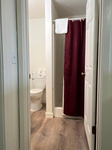 a bathroom with a toilet and a red shower curtain at Port Townsend Inn in Port Townsend