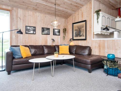 a living room with a brown leather couch and two tables at 8 person holiday home in Ebeltoft in Ebeltoft