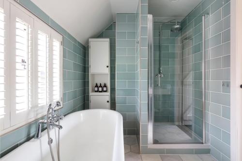 a bathroom with a tub and a shower with blue tiles at Luxury Home, 20 Mins From Goodwood Pet Friendly! in Stoughton