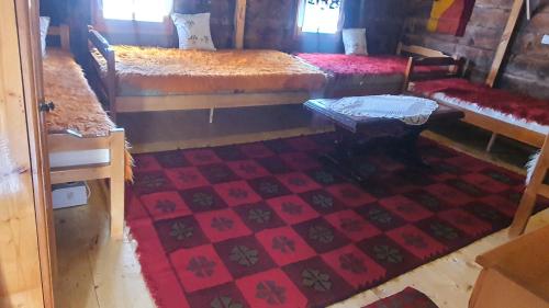 Zimmer mit 2 Betten, einem Tisch und einem Teppich in der Unterkunft ETNO SELO VEZIROV RANČ in Sjenica