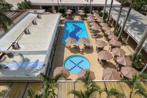 uma vista superior para uma piscina do resort com guarda-sóis e mesas em Hotel Premium Campinas em Campinas