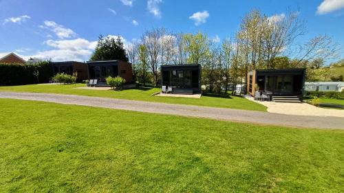 a green yard with two buildings in the background at Luxury Pods at Mornest Caravan Park, Anglesey in Gaerwen