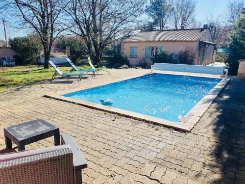 une grande piscine avec deux chaises et une maison dans l'établissement Villa Les Acacias Piscine et Clim, à Saint-Maximin-la-Sainte-Baume