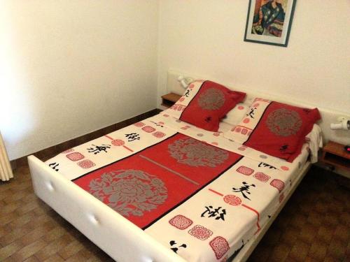une chambre avec un lit avec des draps rouges et blancs et des oreillers rouges dans l'établissement Résidence Héliopolis Bâtiment Ab - Studio cabine 4 pers Héliopolis Bât. AB MAE-2954, au Cap d'Agde