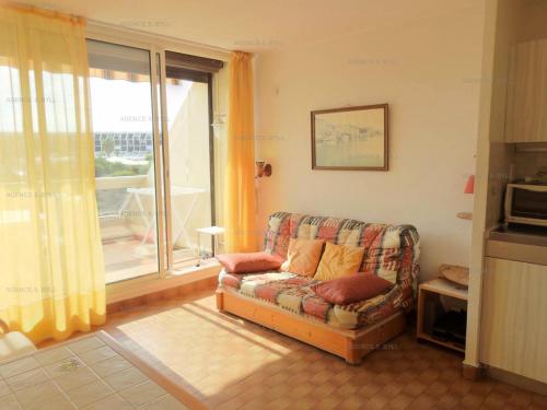 un salon avec un canapé et une grande fenêtre dans l'établissement Résidence Héliopolis Bâtiment Ab - Studio cabine 4 pers Héliopolis Bât. AB MAE-2954, au Cap d'Agde