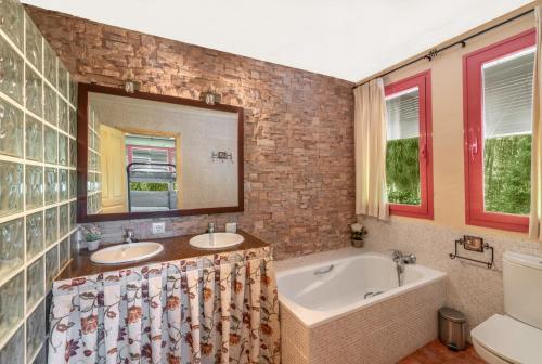 a bathroom with two sinks and a tub and a mirror at El Bosque de la Herrezuela in Guisando