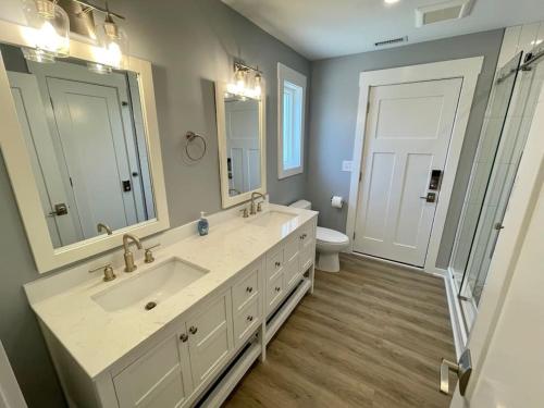 een badkamer met 2 wastafels, een toilet en een spiegel bij Saltmeadow House in Surf City