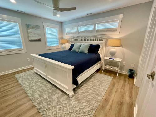 een slaapkamer met een bed met een blauw dekbed en 2 ramen bij Saltmeadow House in Surf City