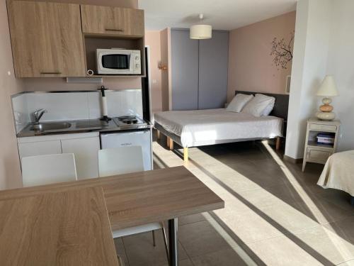 ein kleines Apartment mit einer Küche und einem Bett in der Unterkunft Studio 1 avec piscine & vue sur la baie d'Ajaccio in Alata