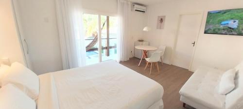 a white room with a bed and a table with chairs at Parador Búzios Boutique Hotel in Búzios