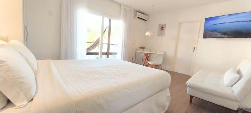 a white bedroom with a white bed and a chair at Parador Búzios Boutique Hotel in Búzios