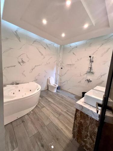 a bathroom with a tub and a toilet and a sink at Havre de paix in Cotonou