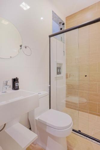 a white bathroom with a toilet and a shower at Pousada e Adega Lapa do Lobo in Conservatória
