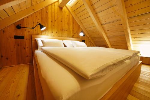 a bed in a room with a wooden ceiling at Alpine Retreat Apartments Šurc in Rateče