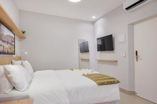 a white bedroom with a white bed and a tv at Pousada e Adega Lapa do Lobo in Conservatória