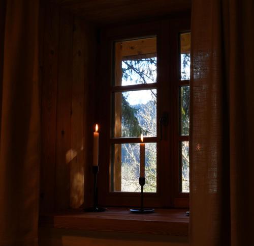 two candles sitting in front of a window at Alpine Retreat Apartments Šurc in Rateče