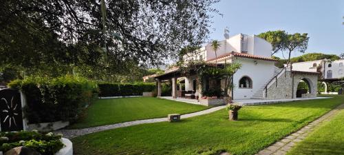 a large white house with a green yard at Villa Amantea in Santa Margherita di Pula