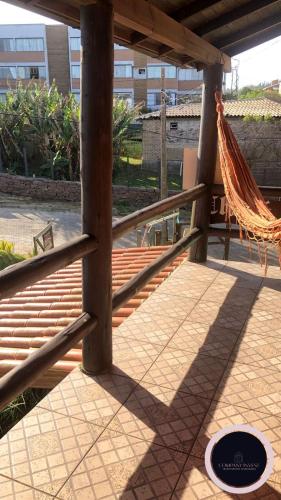 een hangmat hangend aan een houten hek op een patio bij Chalé no Farol de Santa Marta in Laguna