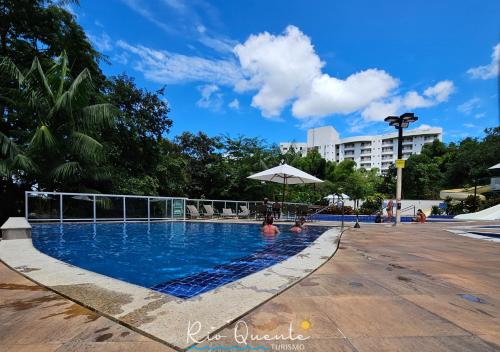 a swimming pool with two people sitting under an umbrella at Hotel Park Veredas in Rio Quente