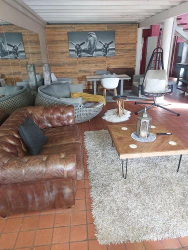 a living room with a leather couch and tables at Gallery Guesthouse (La Sky Villa) in Gqeberha