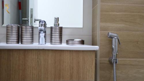 een wastafel in de badkamer met een kraan en stapels munten bij Wanderlust 2BR Apartment in Abu Dhabi