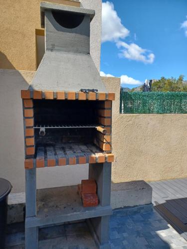 un horno de ladrillo sentado en la parte superior de un patio en maison cosy climatisée avec piscine et jardin en Calenzana