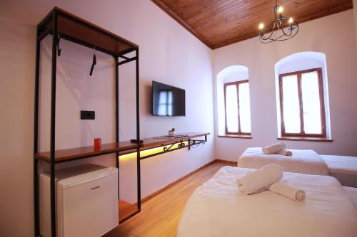 a bedroom with two beds and a desk and two windows at Grey Stone in Gjirokastër