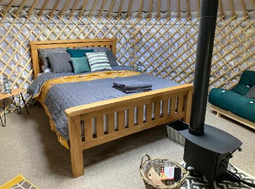 Eisa Yurt في يورك: غرفة نوم بسرير خشبي وموقد خشب