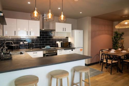 a kitchen with white cabinets and a table with stools at Turkish Baths Retreat, City Centre in Sheffield