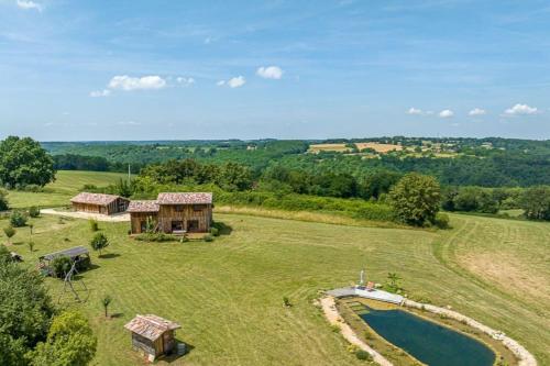 une vue aérienne sur une maison dans un champ avec un étang dans l'établissement Maison Piscine Naturelle, à Sainte-Croix-de-Beaumont