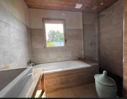 une salle de bain avec une baignoire et une fenêtre dans l'établissement Maison Piscine Naturelle, à Sainte-Croix-de-Beaumont