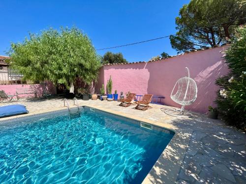 - une piscine avec 2 chaises et une maison rose dans l'établissement Appartement dans villa, parking, accès piscine, au Plan-de-la-Tour