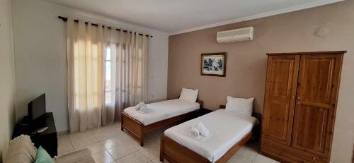 a small room with two beds and a window at Studios Anagnostou in Skala Marion