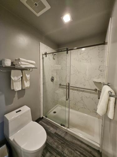 a bathroom with a toilet and a glass shower at Signature Inn Santa Clara in Santa Clara