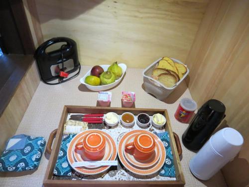 a table with plates of food and a basket of fruit at Refúgio da Montanha in Urubici