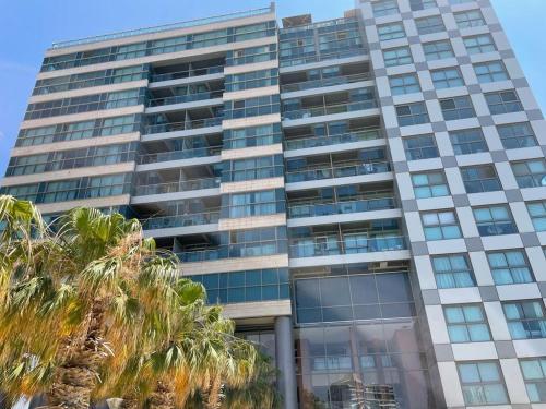 a tall building with palm trees in front of it at Hotel Apartment okeanos bamarina in Herzliya Pituah