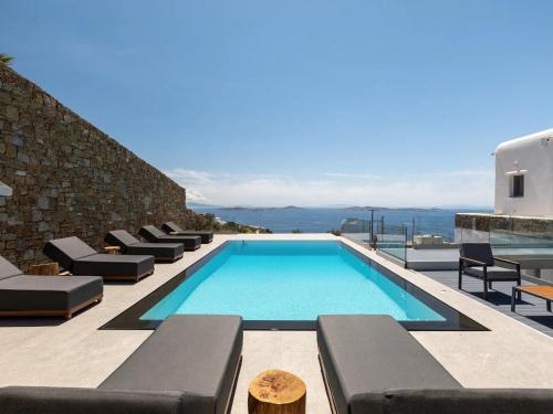 a swimming pool with lounge chairs on a house at Stunning Oceanview Mykonos Villa | 5 Bedrooms | Villa Perseus | Amazing Location Overlooking Sea & Private Pool | Faros in Fanari