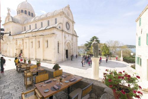 a large building with tables and a clock tower at Apartment AMare in Šibenik