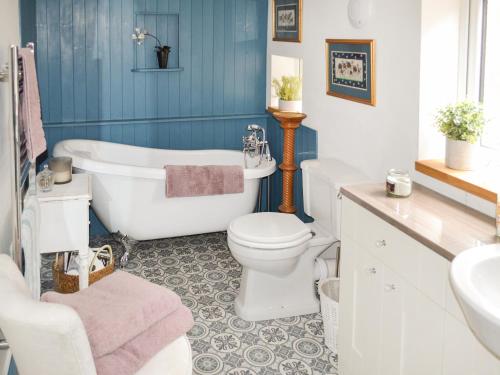 a bathroom with a tub and a toilet and a sink at Victory Hall Cottage in Spilsby