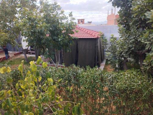 eine kleine Hütte in einem Garten mit Bäumen und Sträuchern in der Unterkunft DAR EL3EZ in Sicca Veneria