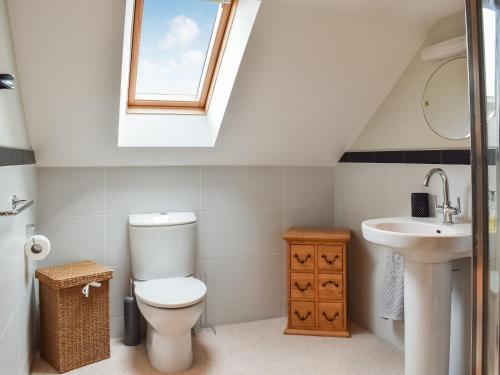 baño con aseo y lavabo y ventana en Hoopers End en Sedgwick
