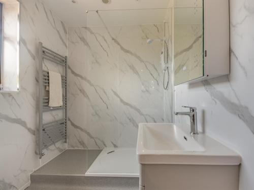 a white bathroom with a sink and a shower at Hwylfa Ddafydd in Llysfaen