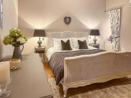 sypialnia z łóżkiem, 2 lampami i stołem w obiekcie Sykelands Cottage w mieście Ravensworth
