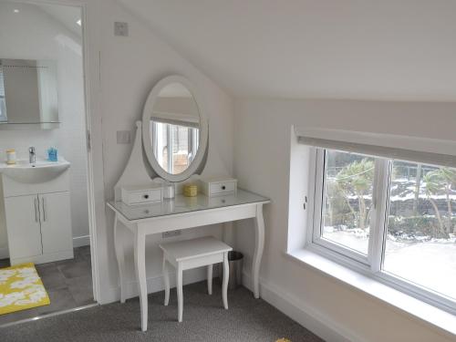 a white bathroom with a sink and a mirror at Penfose Apartment in Mevagissey