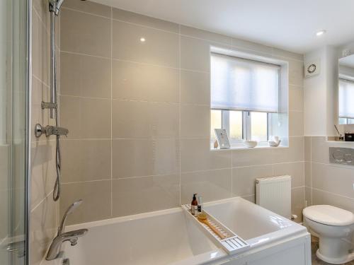 a bathroom with a bath tub and a toilet at Malting Cottage 