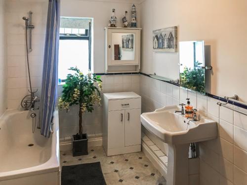 a bathroom with a sink and a bath tub and a sink at Longtye Cottage in Swalecliffe