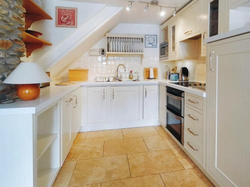 a kitchen with white cabinets and a staircase at The Popples in Ivybridge